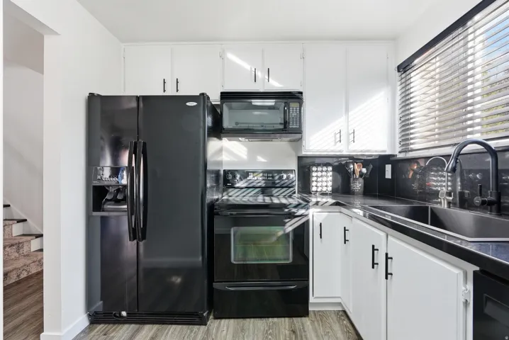 Kitchen with white cabinets, black appliances