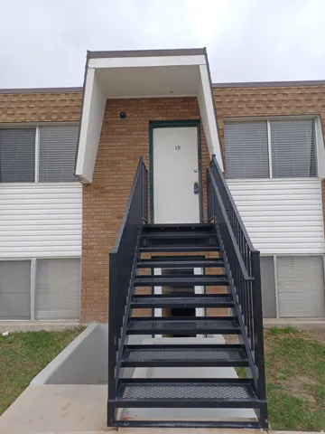 Exterior features a brick and white siding facade with a prominent black metal staircase leading to a white entry door