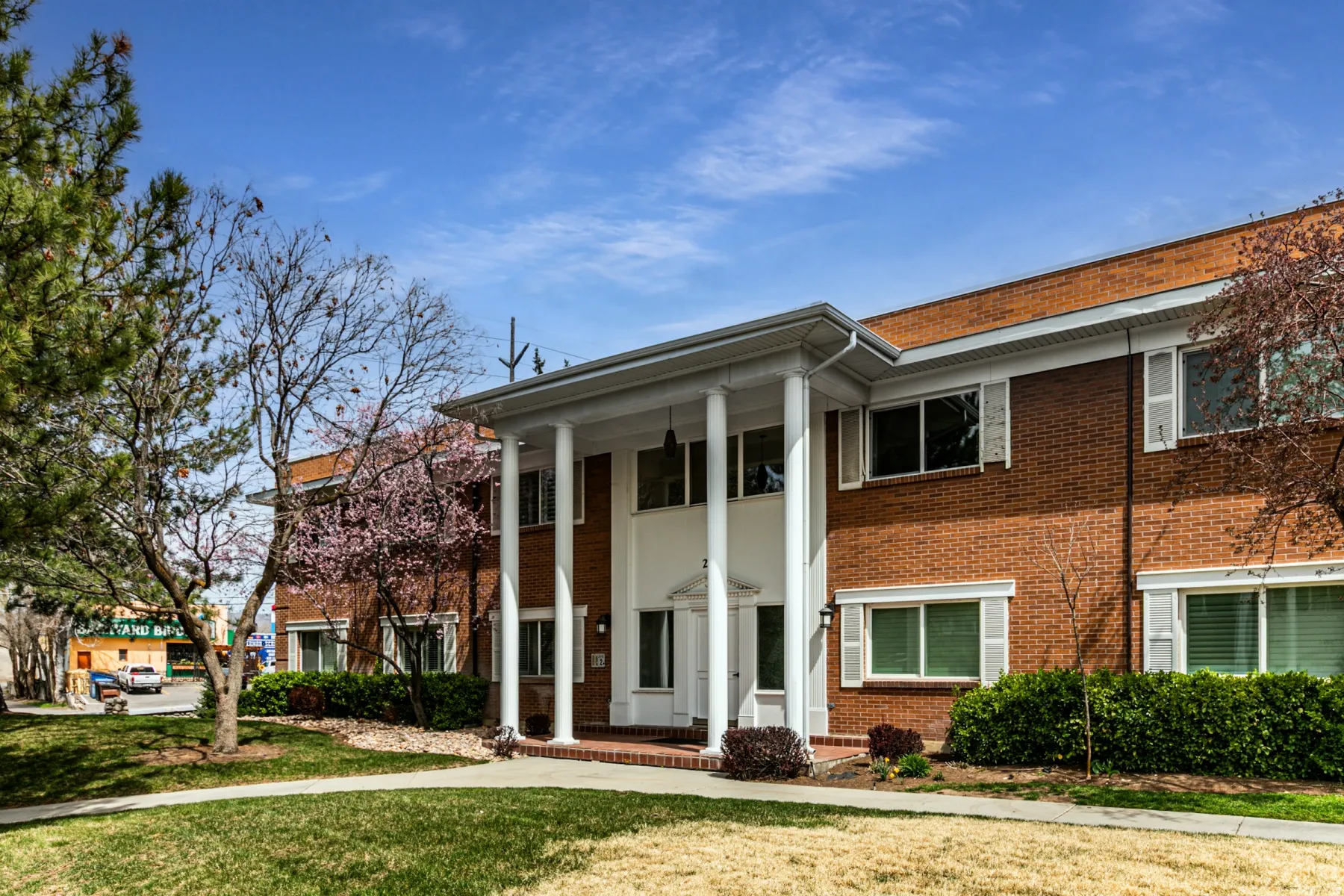 Greek revival inspired property with brick siding, a front yard, and covered porch