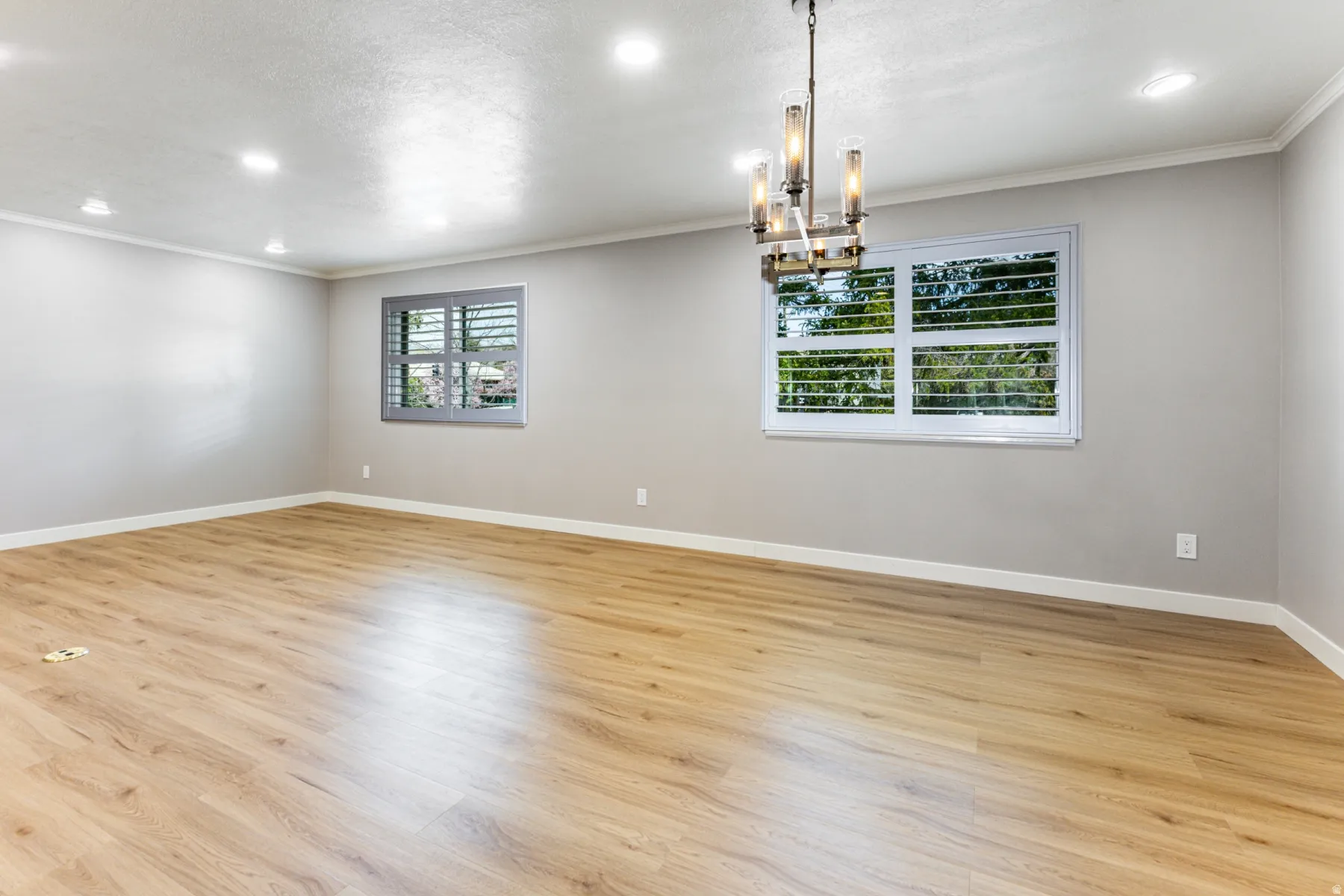 Spare room featuring a chandelier, crown molding, and light wood-type flooring