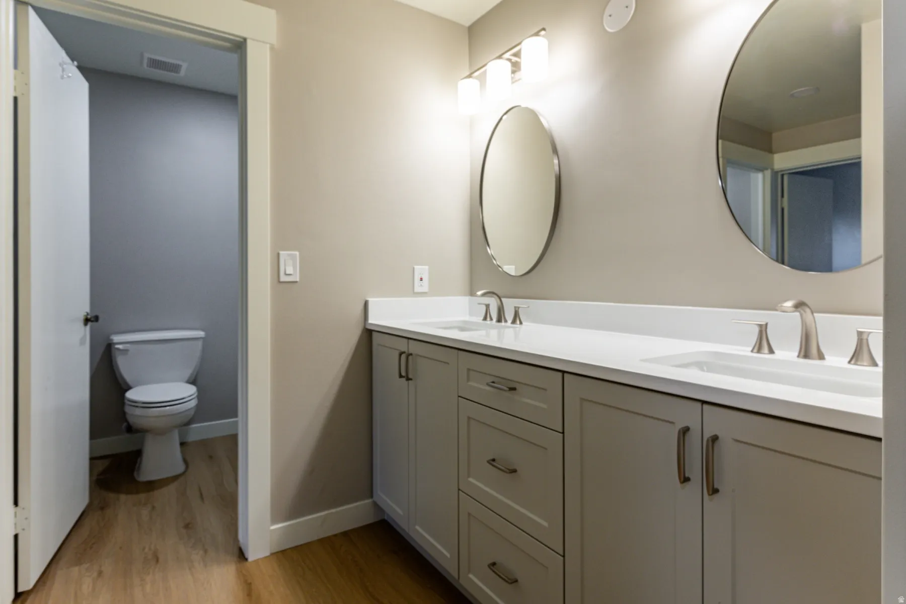 Bathroom with double vanity and light wood-style flooring