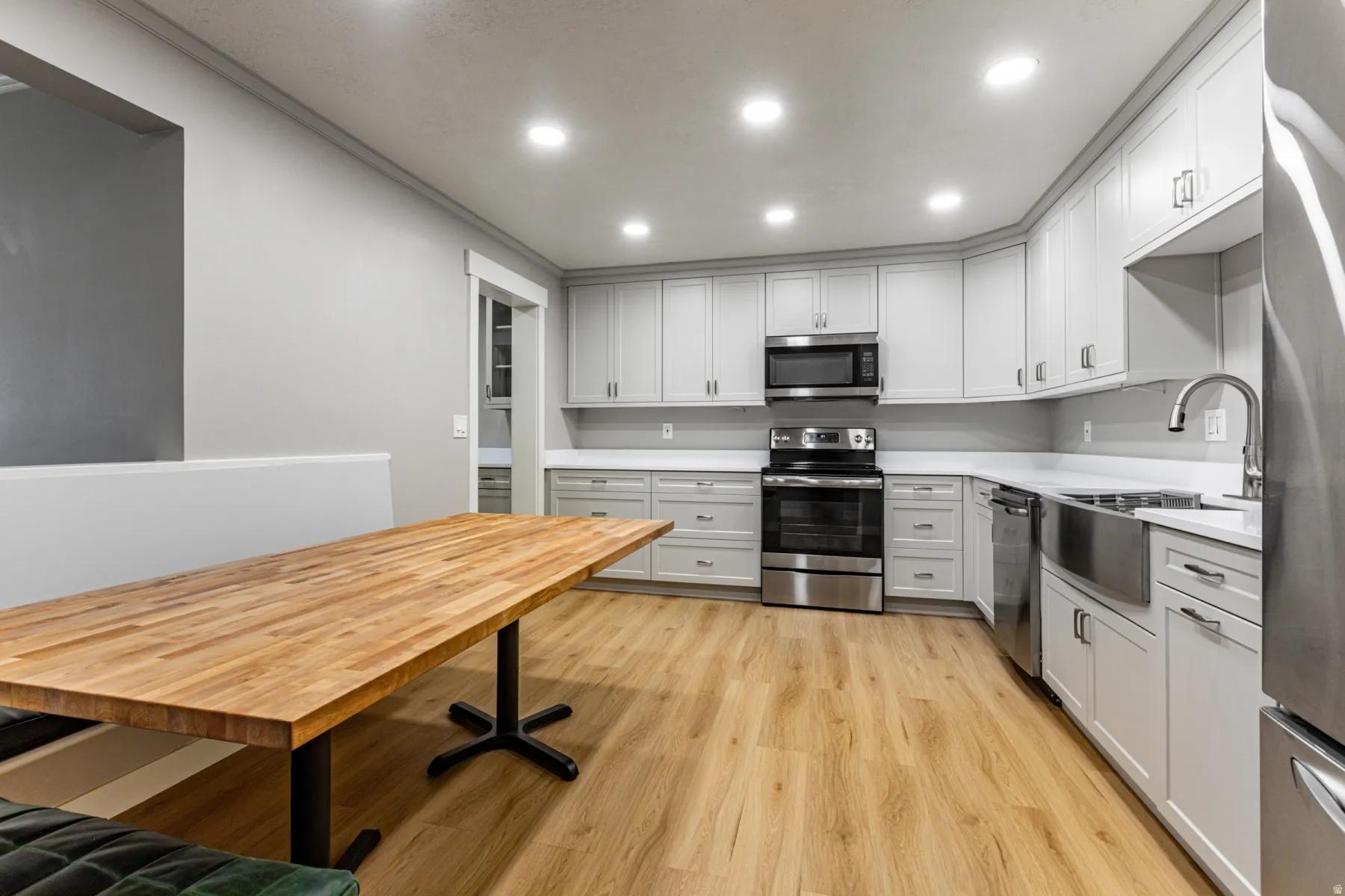 Kitchen with stainless steel appliances, light wood-style floors, recessed lighting, and white cabinets