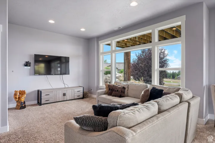 Living area featuring light carpet, recessed lighting, and a textured ceiling