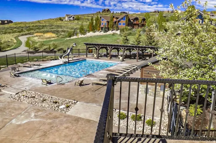 Community pool with a water slide and a patio