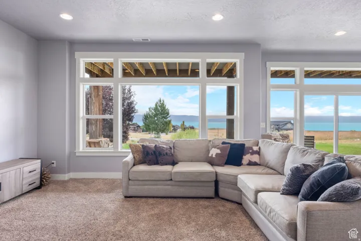 Living area featuring a water view, recessed lighting, carpet flooring, and a textured ceiling