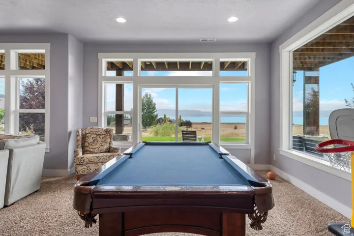 Playroom featuring a water view, billiards, carpet, healthy amount of natural light, and recessed lighting