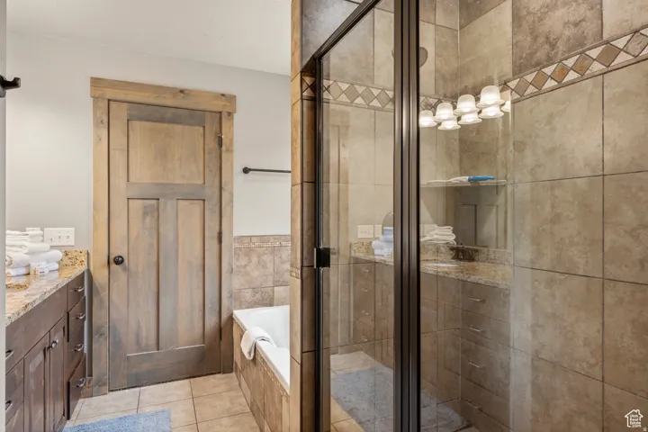 Full bathroom featuring vanity, a garden tub, a stall shower, and light tile patterned floors