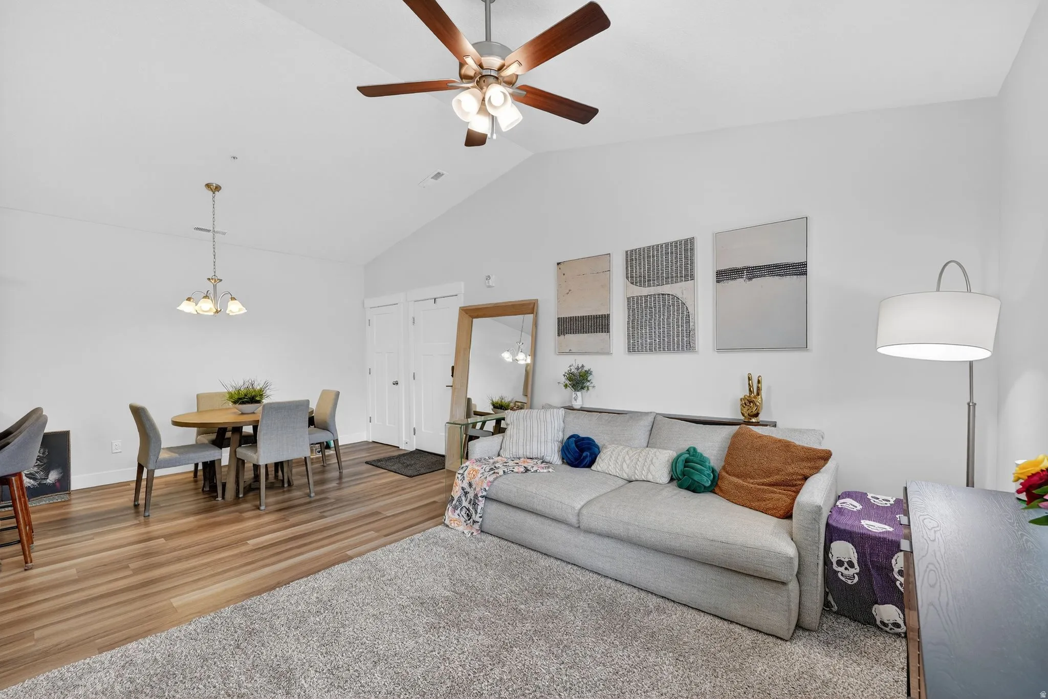 Living room featuring lofted ceiling, a chandelier, a ceiling fan, and wood finished floors