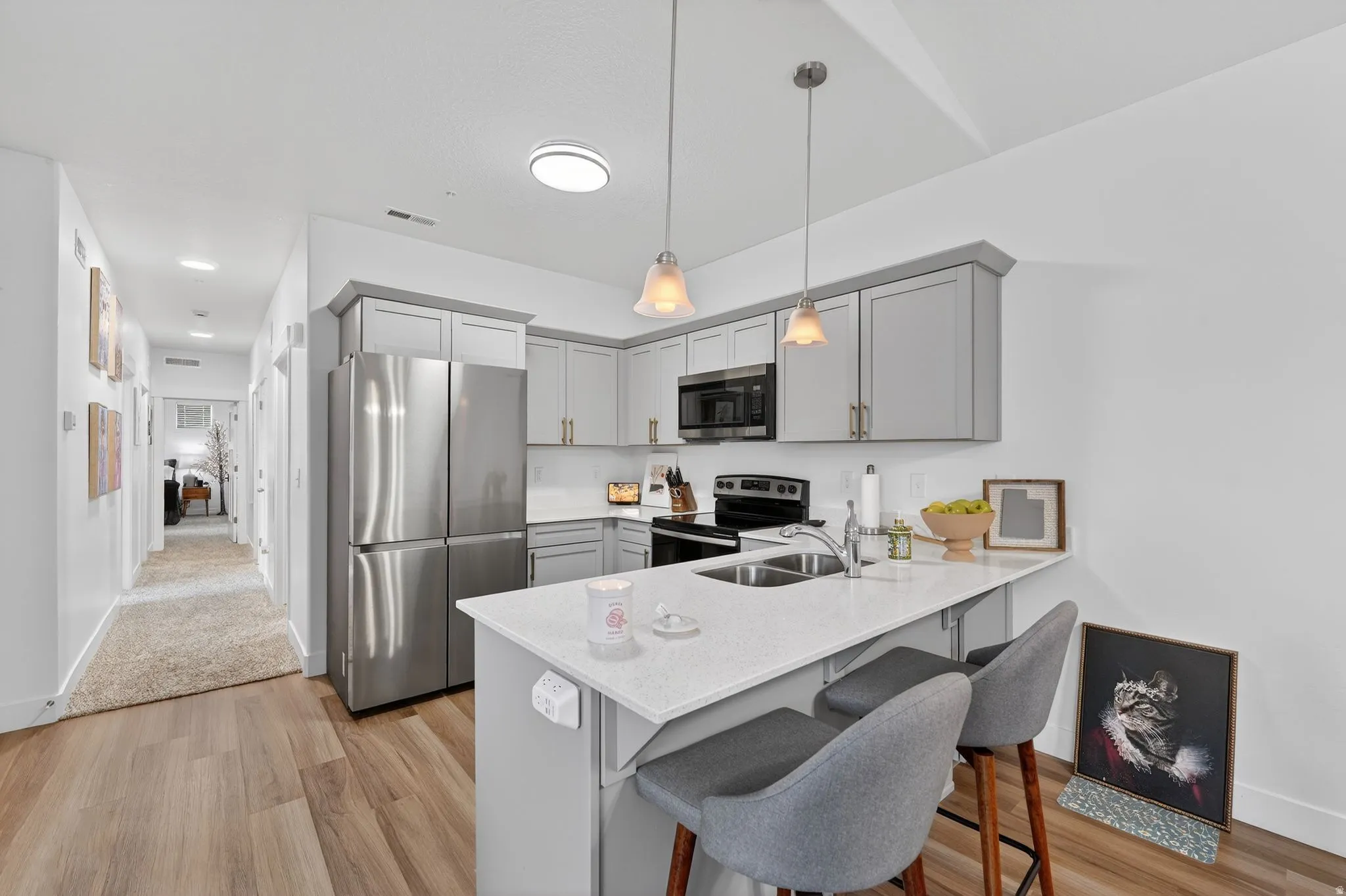 Kitchen with gray cabinets, stainless steel appliances, a kitchen breakfast bar, and a peninsula