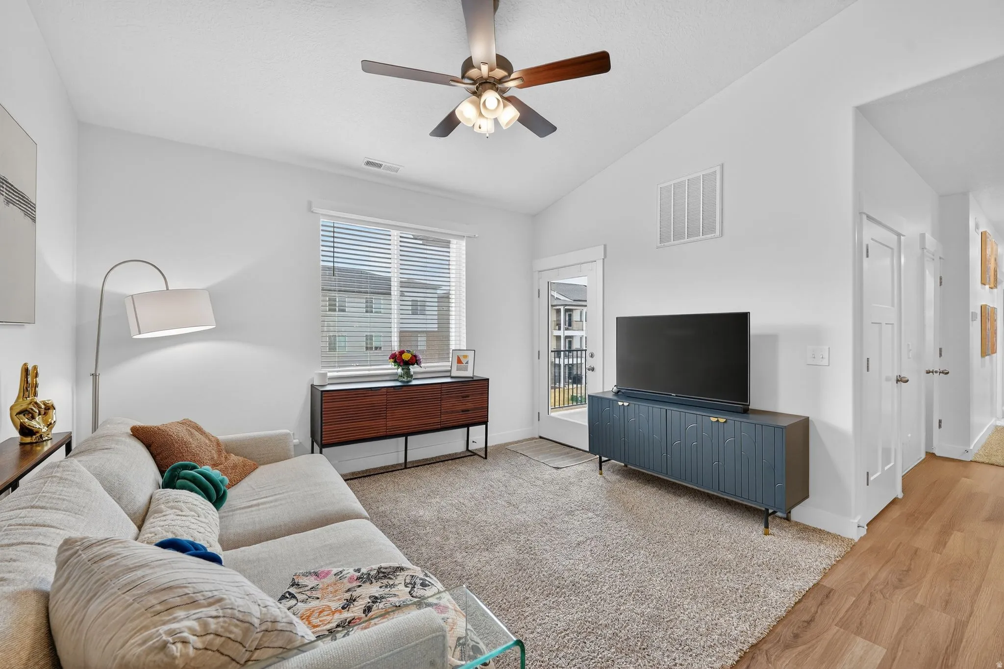Living area with light wood-type flooring, ceiling fan, and lofted ceiling