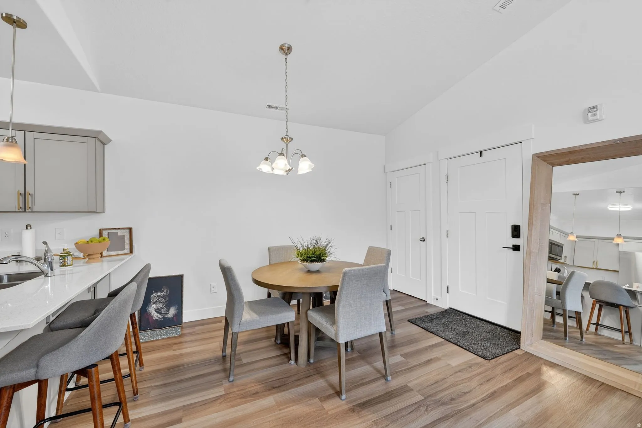 Dining space featuring vaulted ceiling, light wood-style floors, and a chandelier