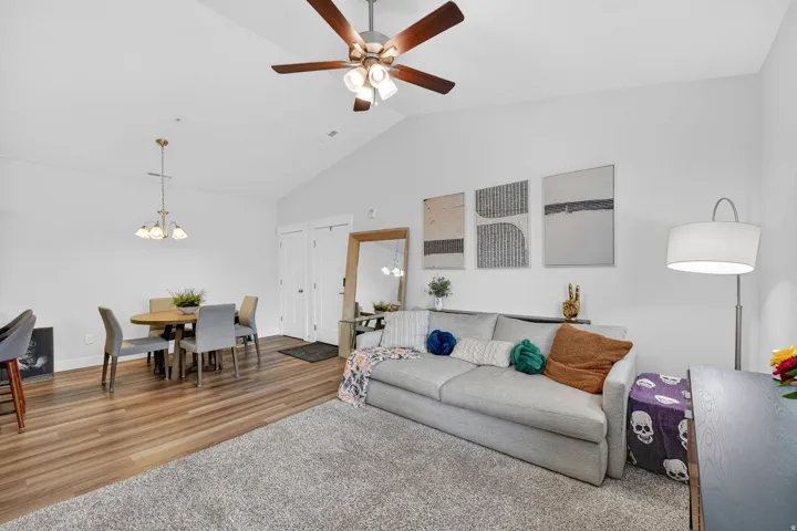 Living room featuring lofted ceiling, a chandelier, a ceiling fan, and wood finished floors
