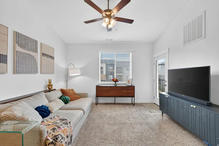 Living area featuring light carpet, a ceiling fan, and lofted ceiling