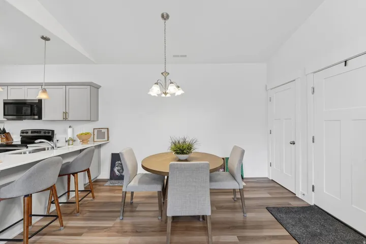 Dining space with suspended lighting, light wood-style flooring, and vaulted ceiling