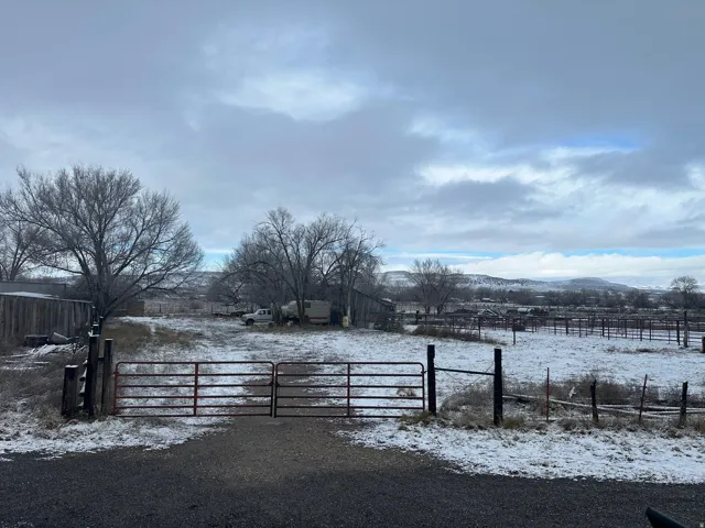 Snowy yard featuring a mountain view and a gate