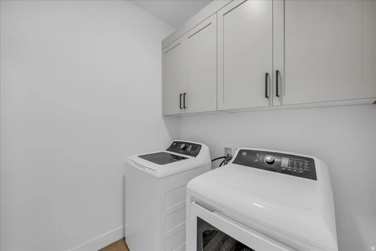 Laundry room with cabinet space, independent washer and dryer, and light wood finished floors