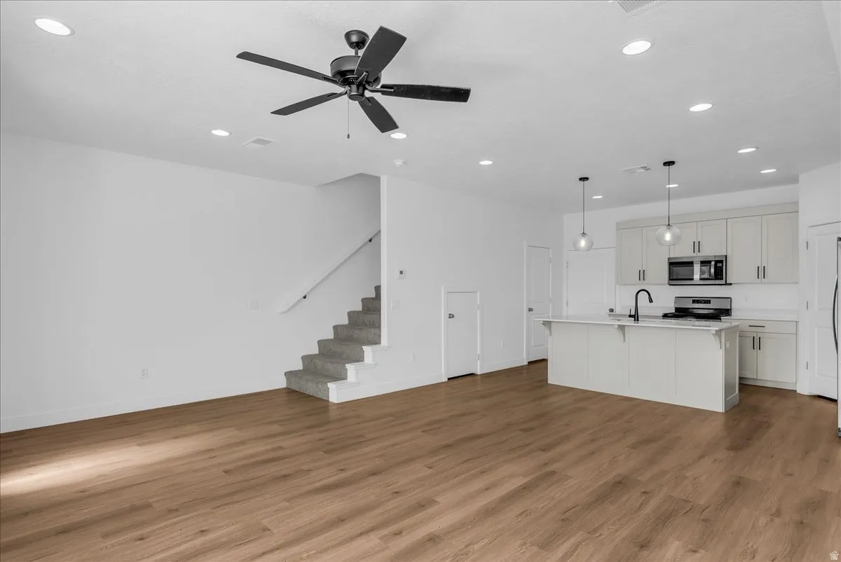 Unfurnished living room featuring a ceiling fan, light wood-style floors, and recessed lighting