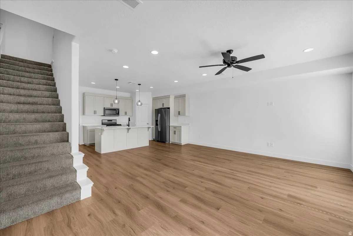 Unfurnished living room with light wood-type flooring, ceiling fan, and recessed lighting