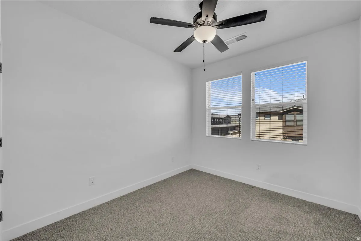 Carpeted spare room with baseboards and ceiling fan