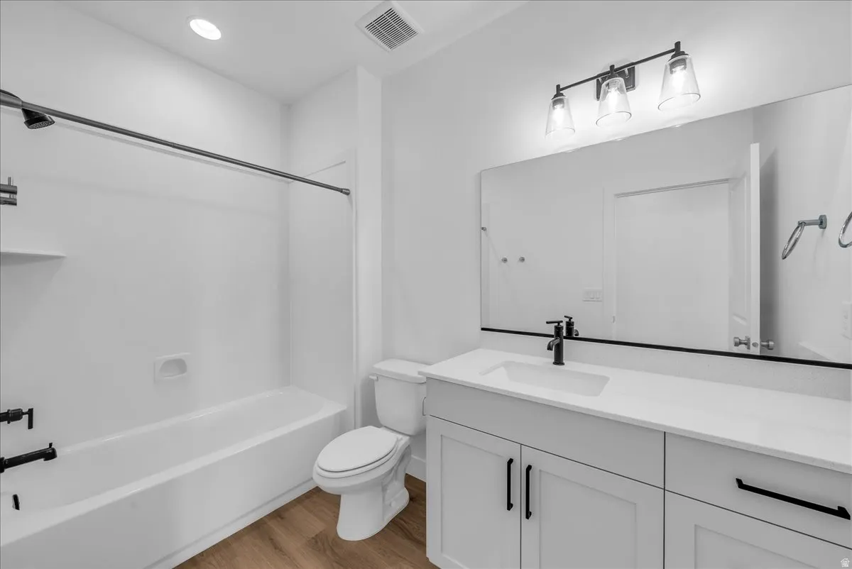 Full bath with vanity, light wood-type flooring, and shower / washtub combination