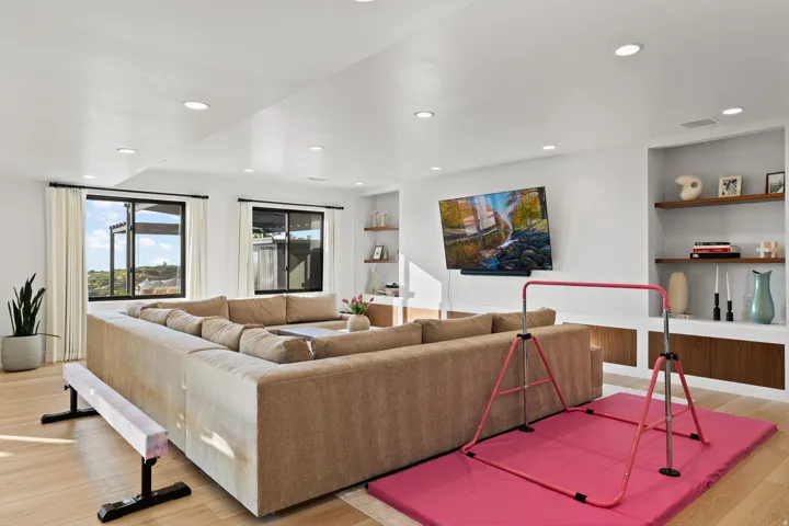 Living area with built in shelves, light wood-style floors, and recessed lighting