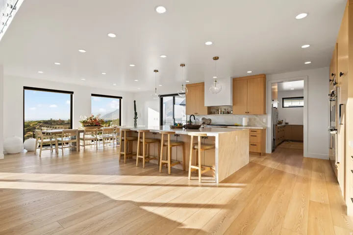 Kitchen with a large island with sink, modern cabinets, light wood-style flooring, a breakfast bar area, and decorative backsplash