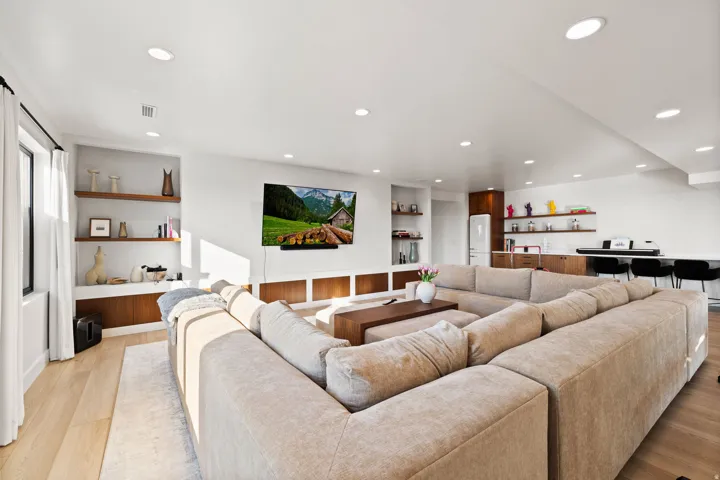 Living area featuring light wood-style flooring, built in shelves, recessed lighting, and bar area