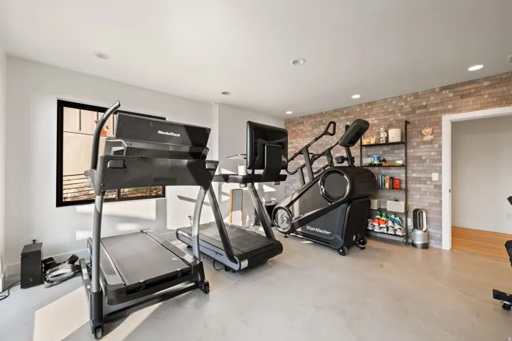 Workout room featuring brick wall, recessed lighting, and finished concrete flooring