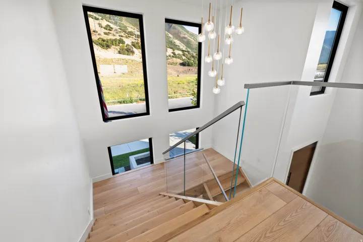 Stairway with hanging lights, plenty of natural light, wood finished floors, and a mountain view