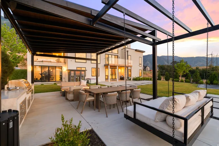 Patio terrace at dusk with a lawn, a mountain view, an outdoor kitchen, outdoor lounge area, and a patio area