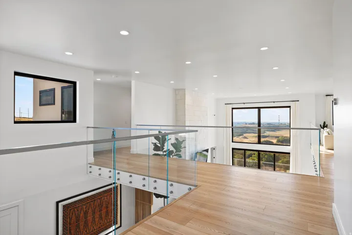Corridor with healthy amount of natural light, light wood-style floors, and recessed lighting