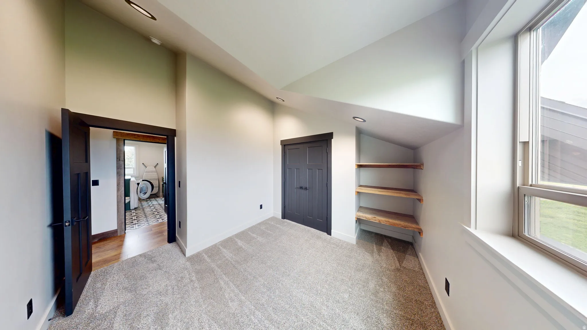 Unfurnished bedroom with light carpet and vaulted ceiling