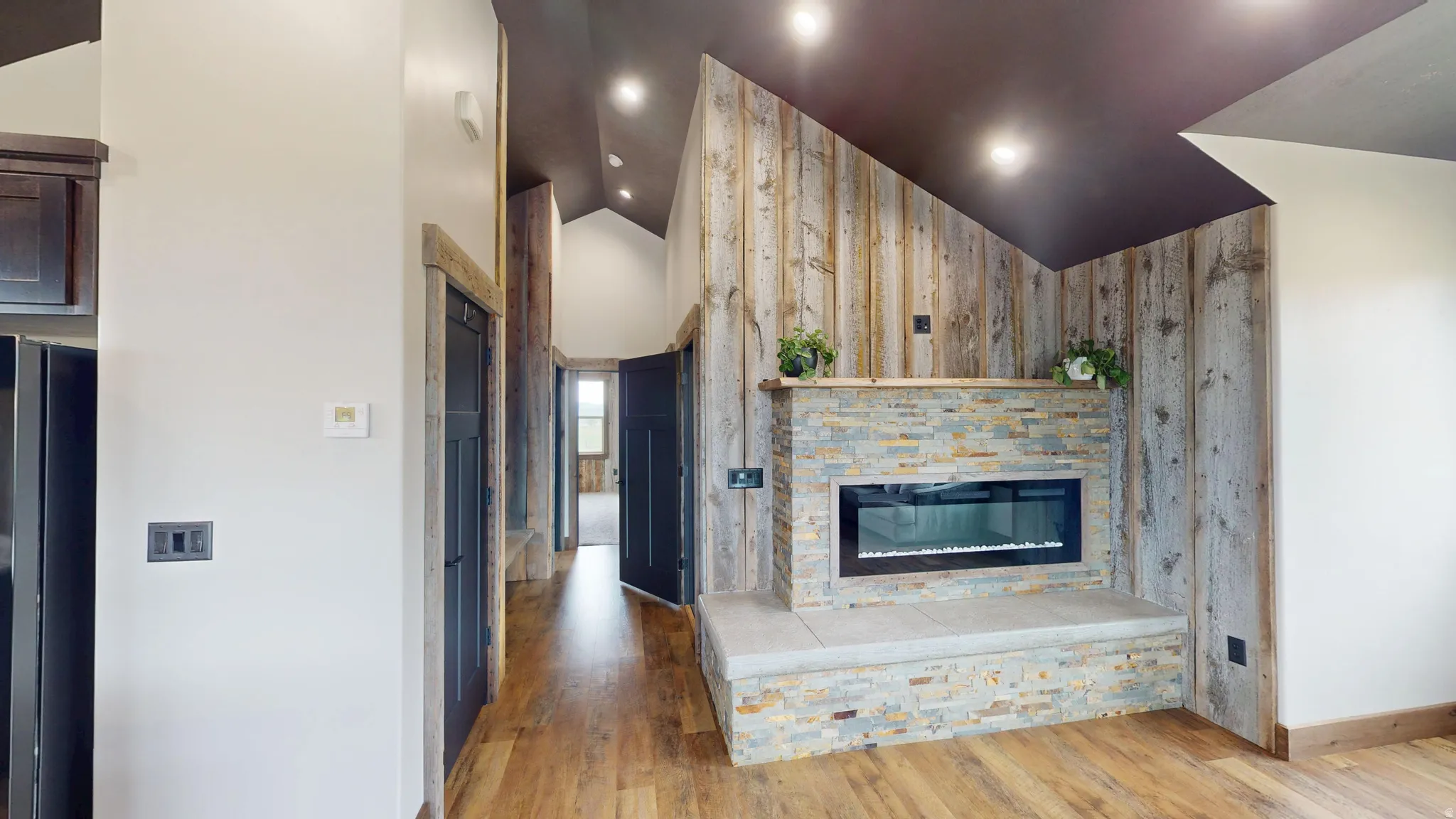 Unfurnished living room featuring lofted ceiling, light wood finished floors, and a fireplace