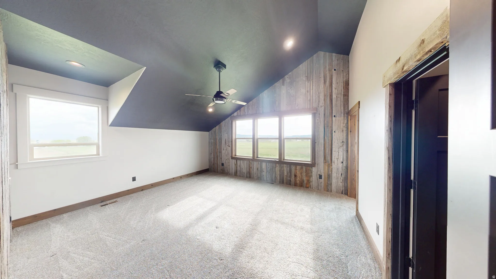Additional living space featuring lofted ceiling, light carpet, a ceiling fan, and wooden walls
