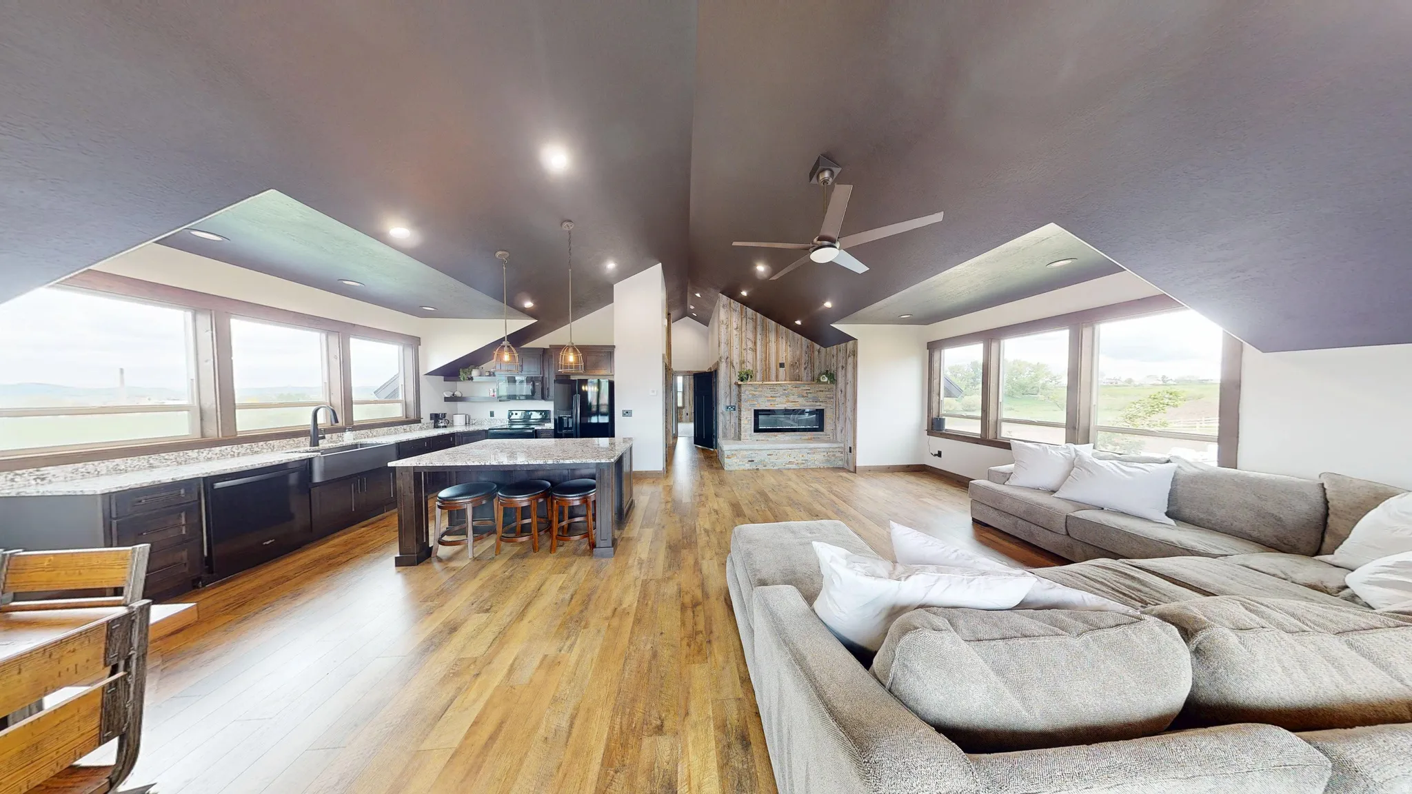 Living area with light wood finished floors, a fireplace, healthy amount of natural light, lofted ceiling, and ceiling fan