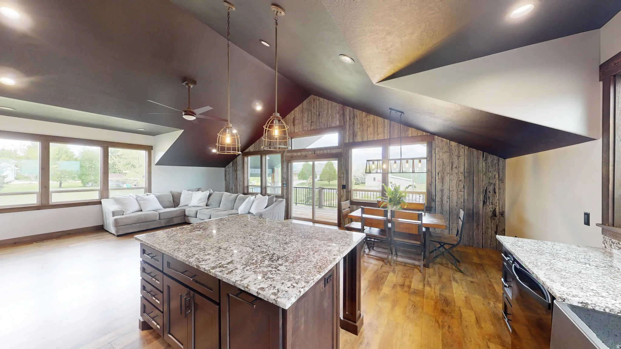 Kitchen with dark wood finish cabinets, a kitchen island, light wood finished floors, light stone counters, and open floor plan