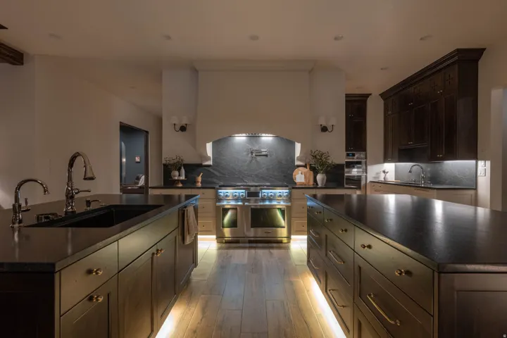 Kitchen with dark wood finish cabinets, a center island with sink, decorative backsplash, and stainless steel appliances