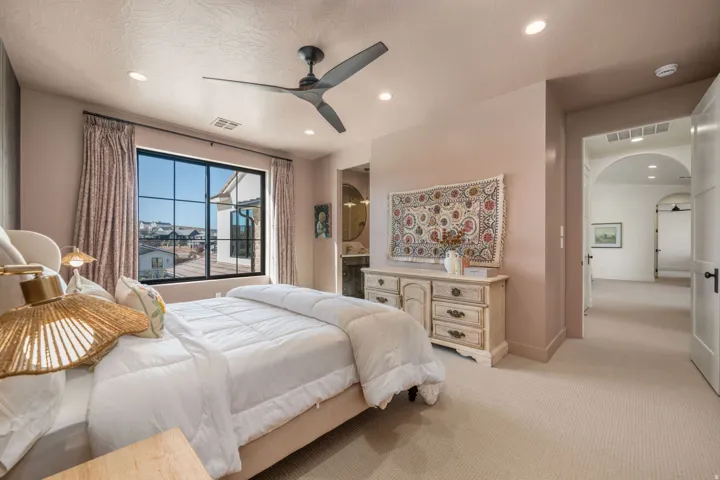 Bedroom with arched walkways, light carpet, a ceiling fan, connected bathroom, and recessed lighting