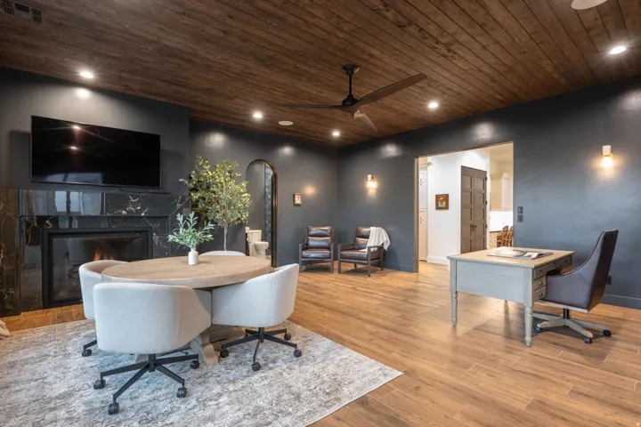 Office space with arched walkways, wood ceiling, a premium fireplace, wood finished floors, and a ceiling fan