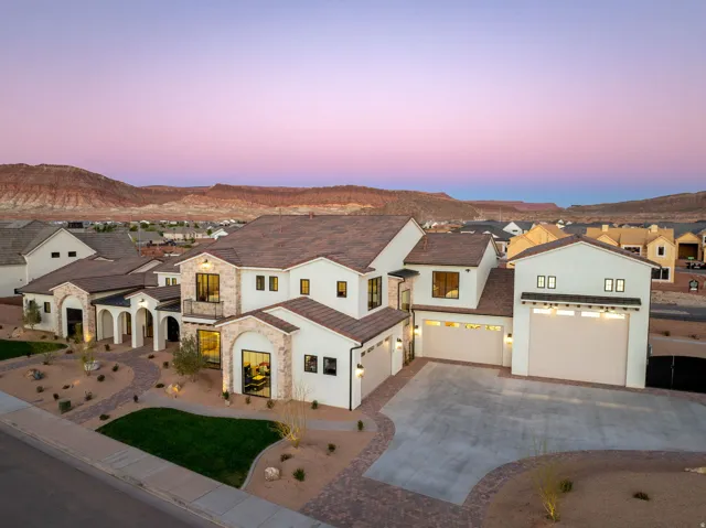 View of front of property featuring a residential view, concrete driveway, stucco siding, stone siding, and a mountain view