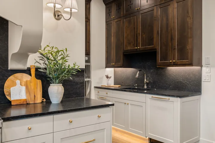 Kitchen featuring backsplash, dark stone countertops, light wood-type flooring, pendant lighting, and dark wood finish cabinetry