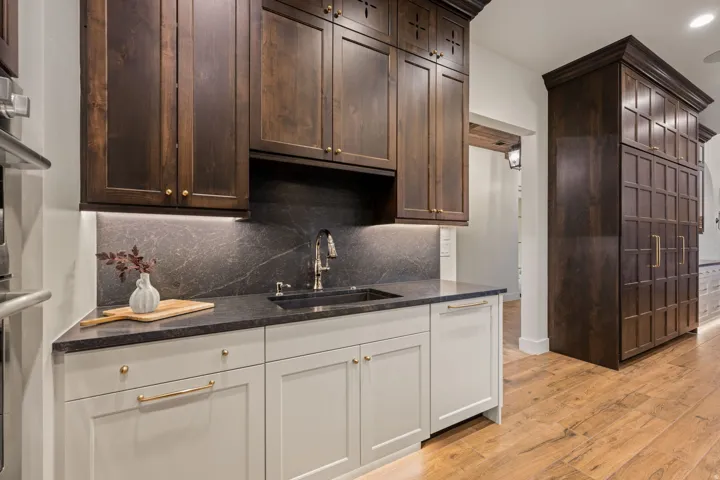 Kitchen featuring light wood-style flooring, dark wood finish cabinetry, dark stone counters, decorative backsplash, and recessed lighting