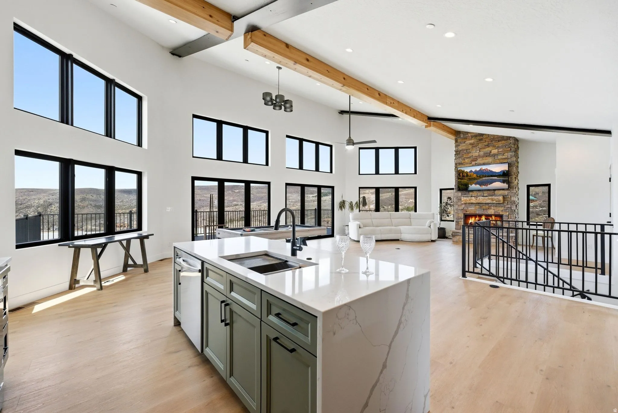 Kitchen featuring a stone fireplace, an island with sink, light wood finished floors, and green cabinetry