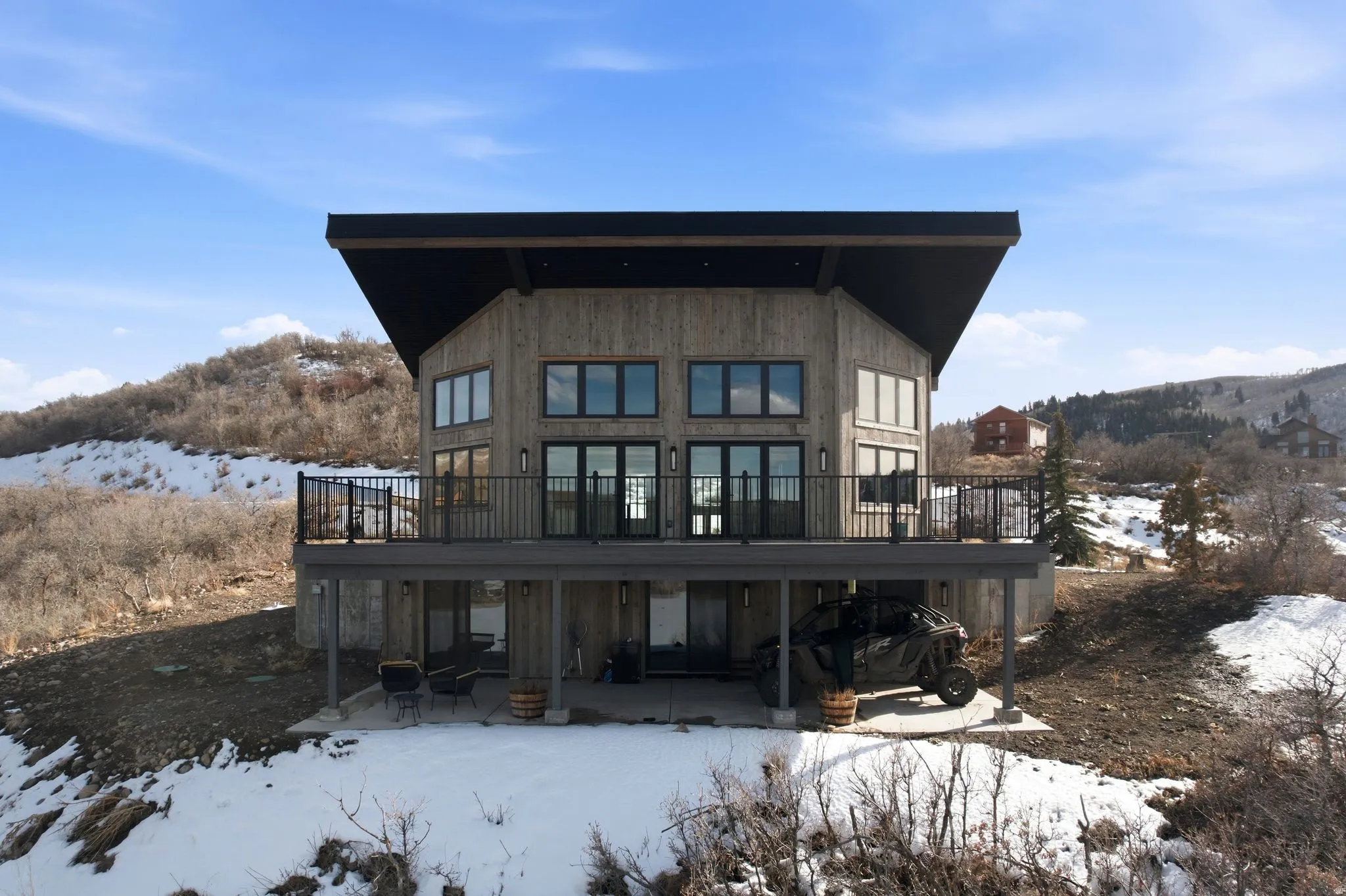Snow covered house with a mountain view and a patio area