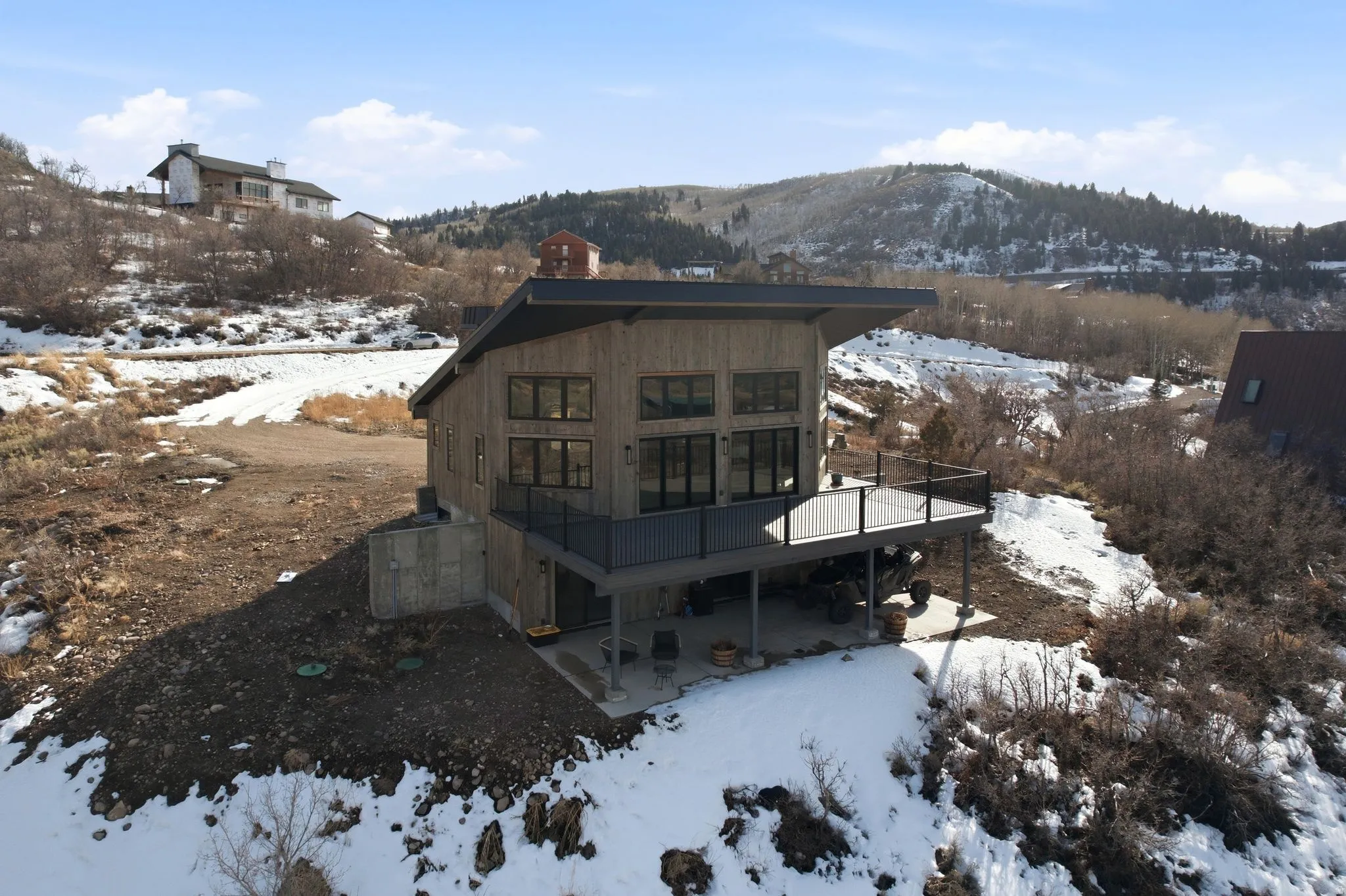 Snow covered rear of property with a patio area, a chimney, and a deck with mountain view