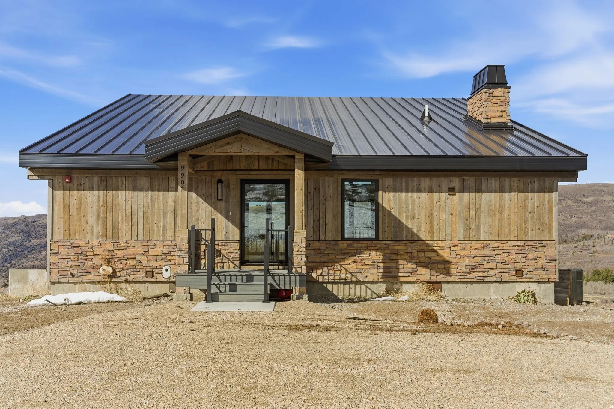 View of front facade featuring stone siding, a metal roof, and a chimney