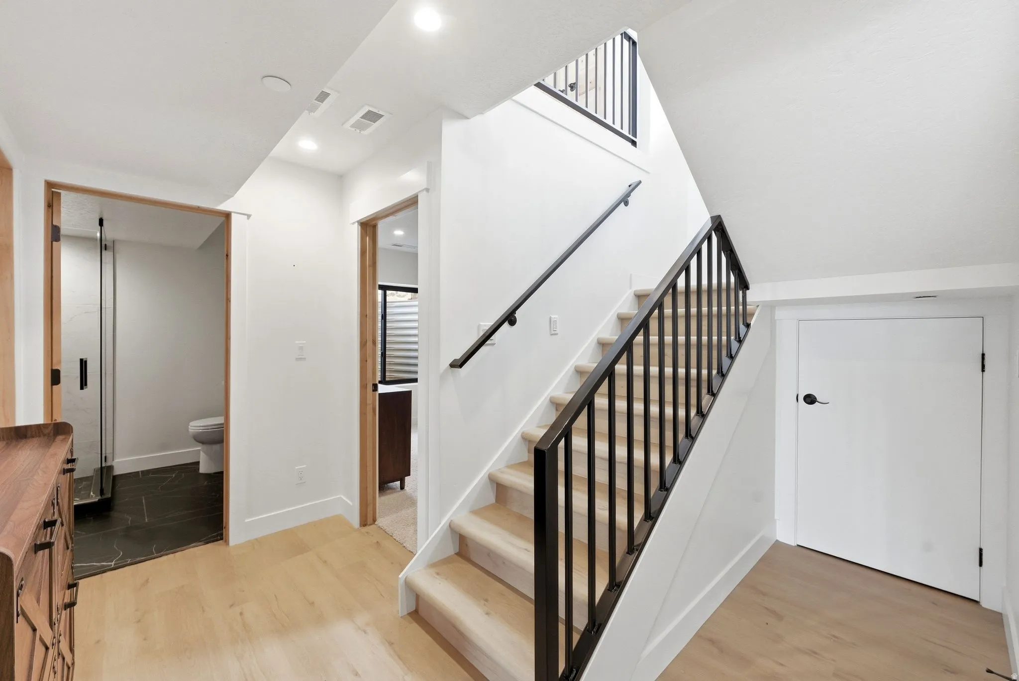 Stairs with wood finished floors and recessed lighting