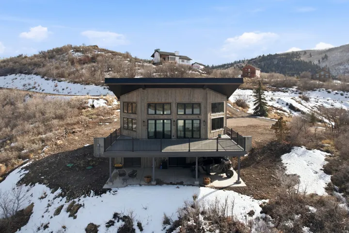 Snow covered house with a deck with mountain and lake views and a 1000 sq ft deck