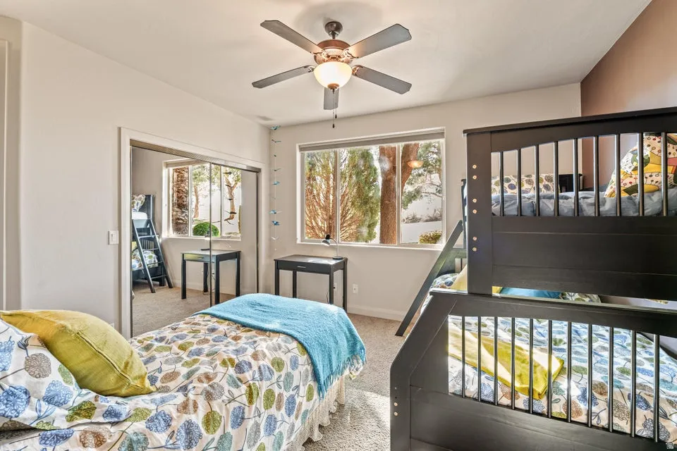 Carpeted bedroom with ceiling fan and a closet