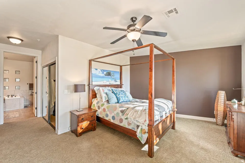Bedroom with light carpet, ceiling fan, a closet, and ensuite bathroom